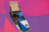 Photographie du fauteuil/pédalier, sur un fond violet/rose en style pop art.